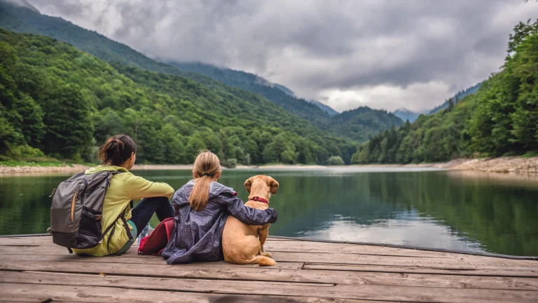 Mother and daughter with a dog resting on a pier