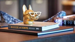 Dog lover desk decor with dachshund ceramic figure wearing glasses and stacked books about wine and music.